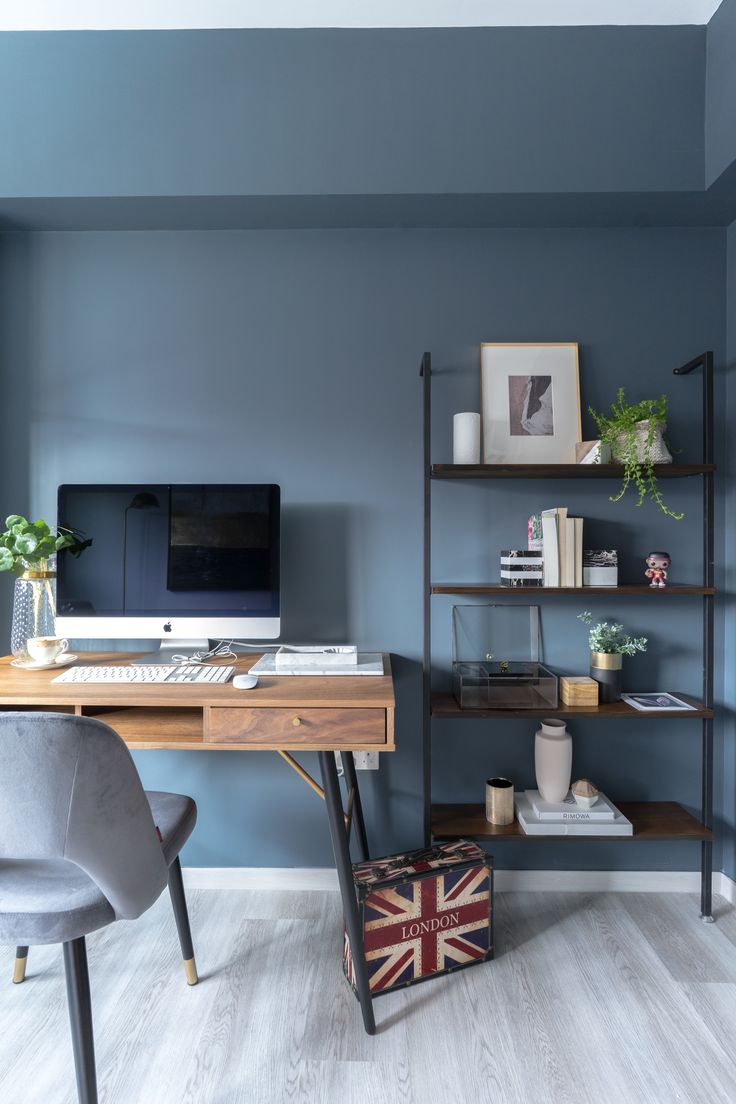 a home office with blue walls and wooden shelves, including a computer monitor on a desk