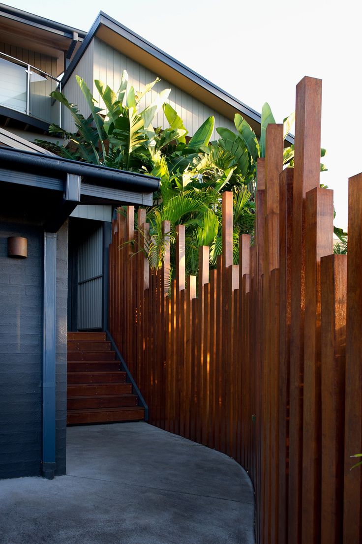 a wooden fence next to a house with plants growing on it