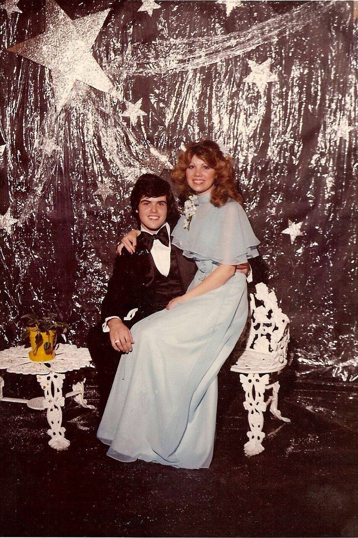 an old photo of two people sitting on a chair in front of a star backdrop