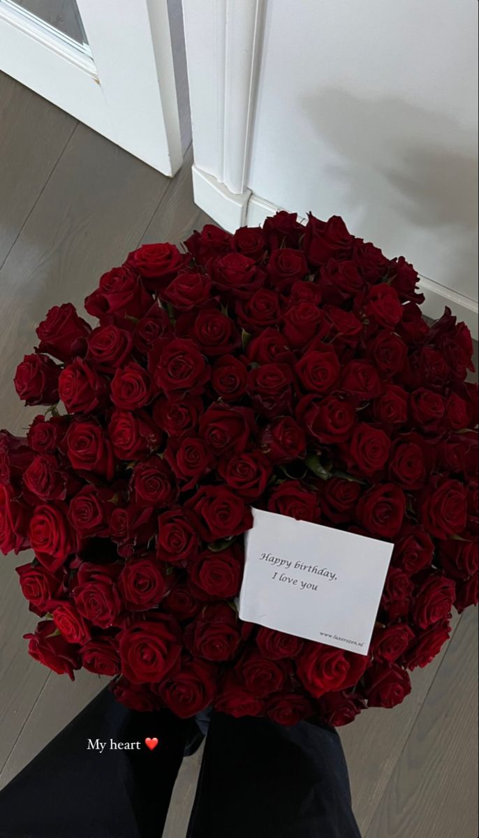 a bouquet of red roses sitting in front of a door with a note on it