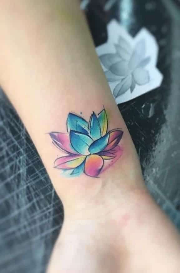 a lotus flower tattoo on the ankle is shown in blue, pink and yellow colors