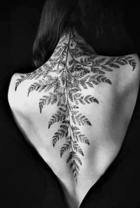 the back of a woman's neck with leaves on it