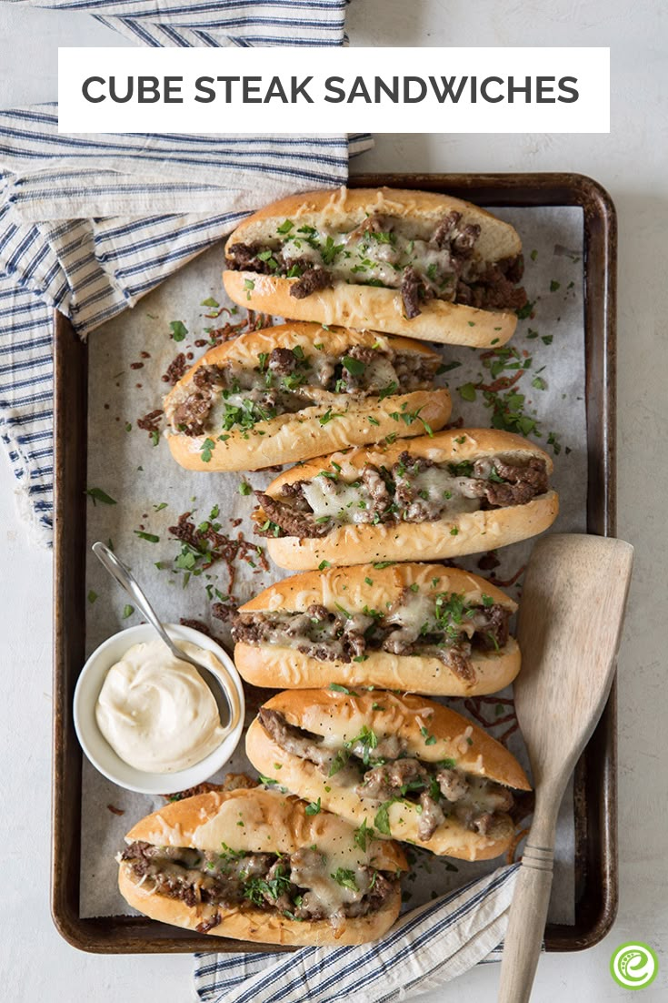 a tray filled with sandwiches covered in meat and cheese next to a bowl of sour cream