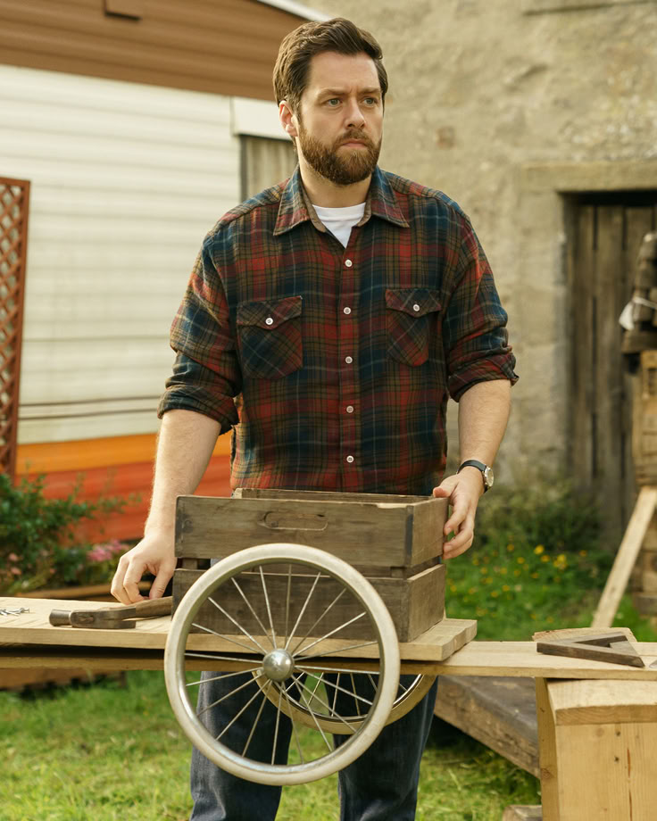 a man standing next to a wooden wheel