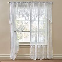 an empty room with a window and white curtains on the windowsill, in front of a hardwood floor