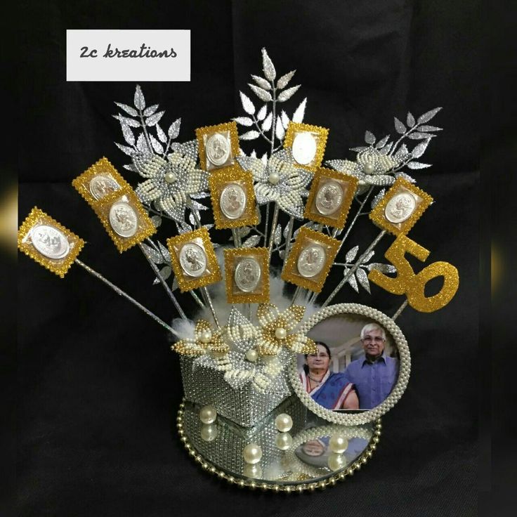 a vase filled with lots of silver and gold decorations on top of a black table