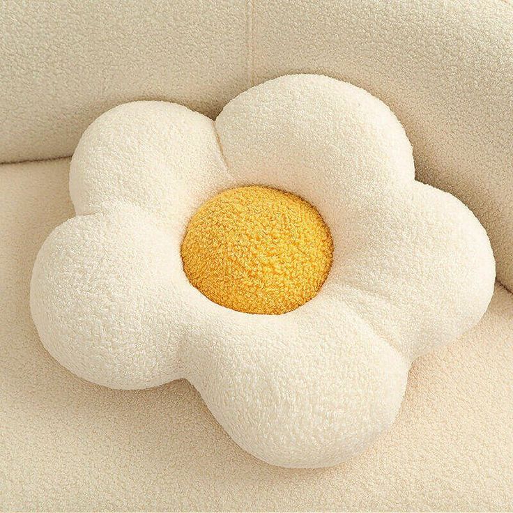 a flower shaped pillow sitting on top of a white couch