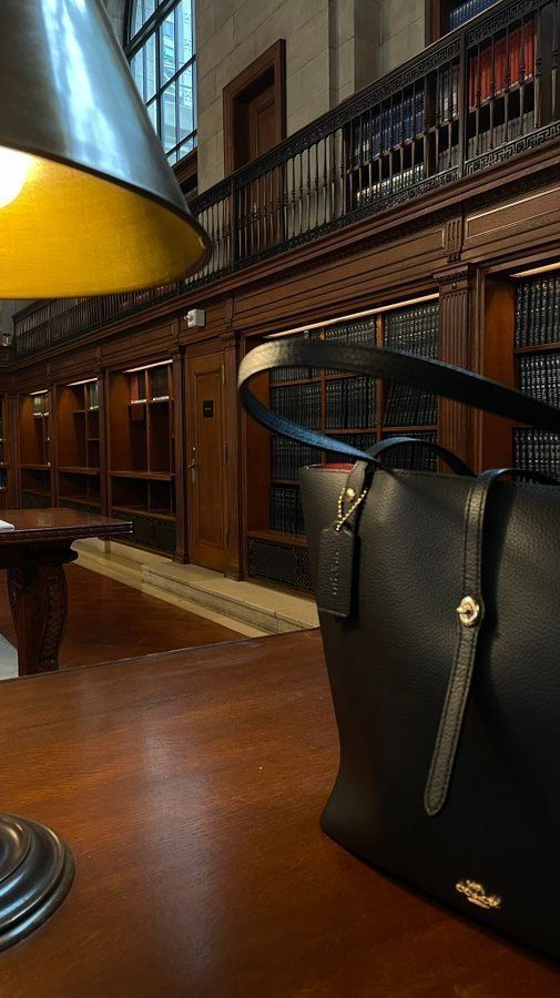 a large black purse sitting on top of a wooden table next to a light fixture