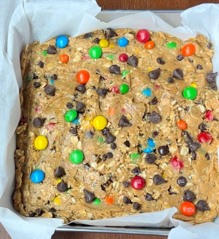 a cookie bar with m & m's and candy bars in it sitting on top of a table