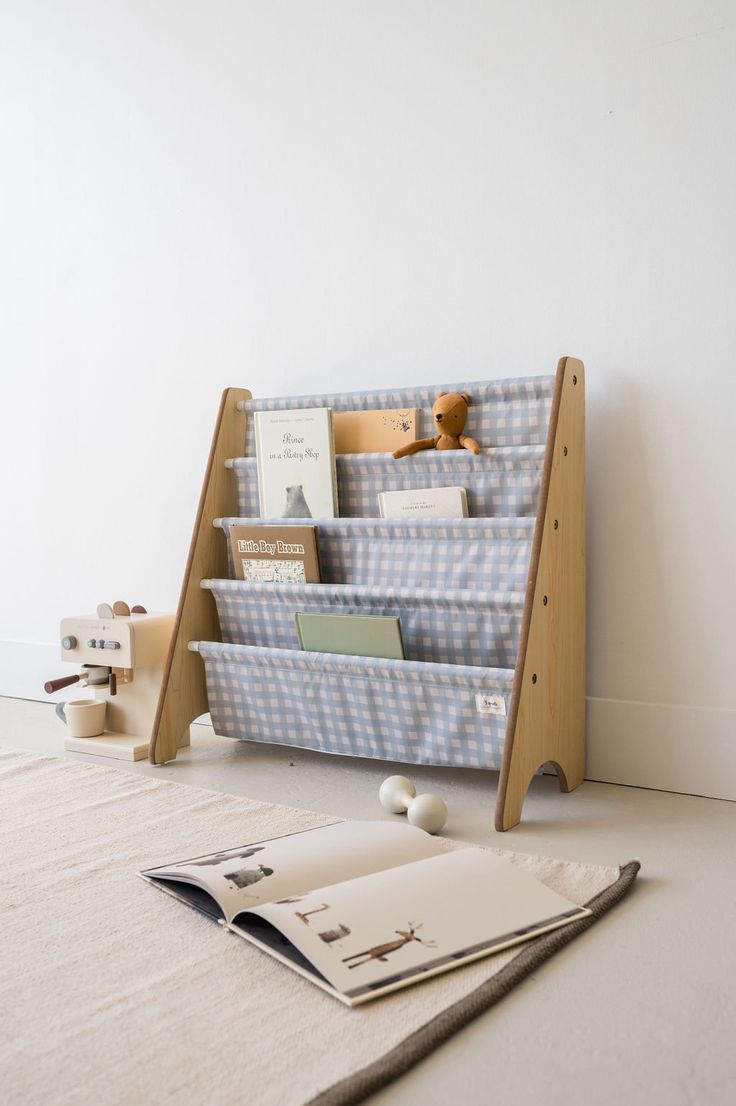 a bookshelf sitting on top of a white floor next to a stuffed animal