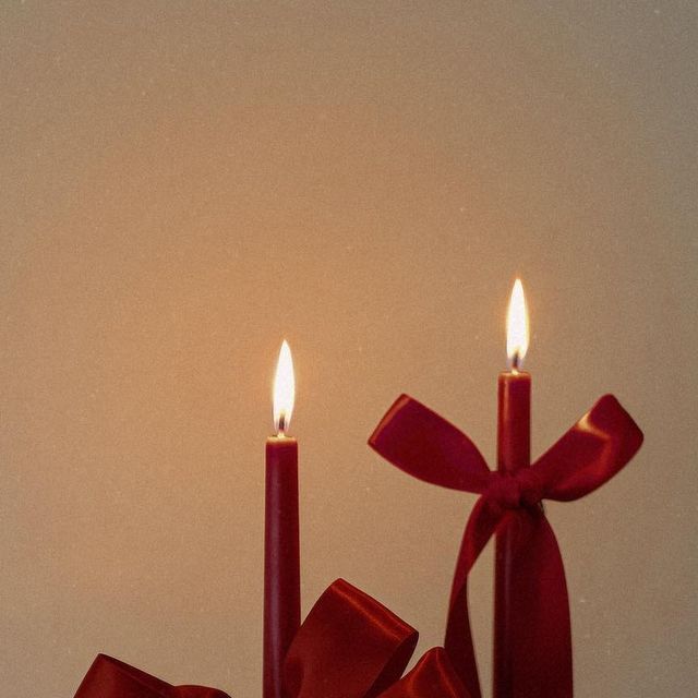 two candles with red bows on them