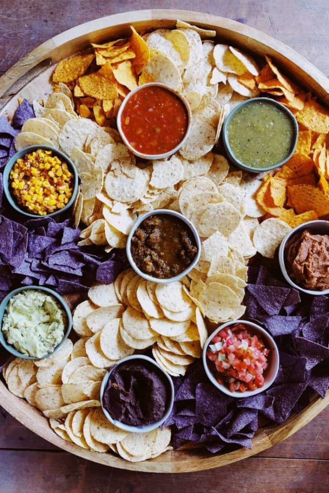 a platter filled with chips, salsa and other condiments