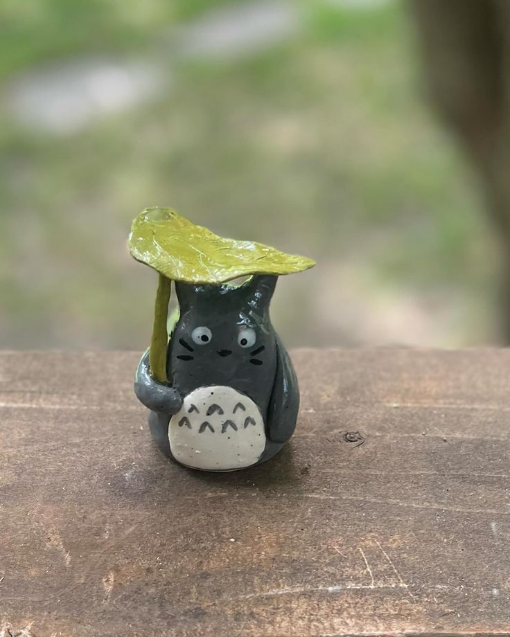 a small black and white cat figurine with a yellow leaf on its head