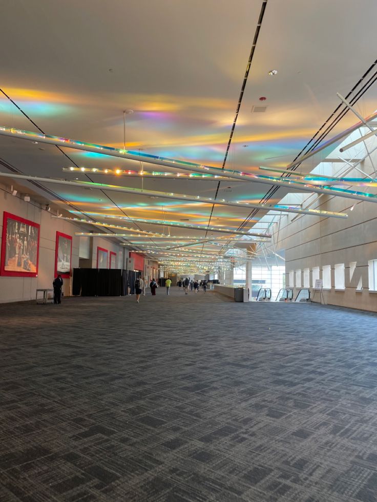 an empty room with people walking around and paintings on the walls in the ceiling above