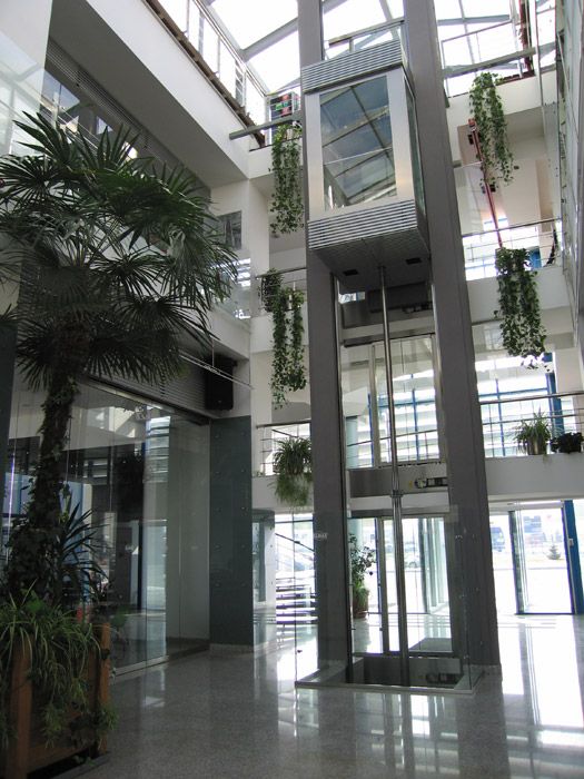 the inside of an office building with plants growing on the walls and glass balconies