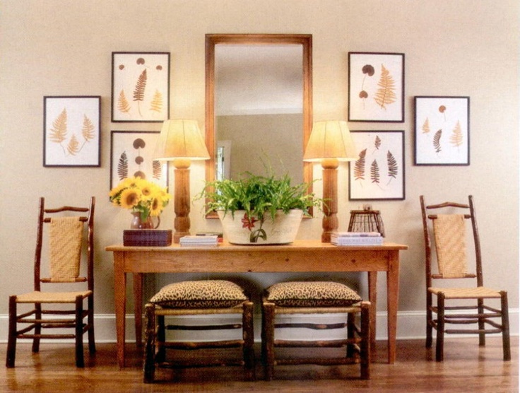 a dining room table with four chairs and a mirror on the wall above it is decorated with plants