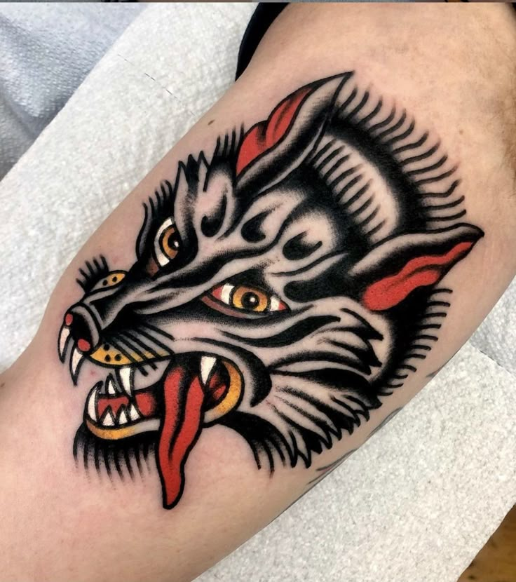 a black and red tattoo on the leg of a man with an angry cat's head