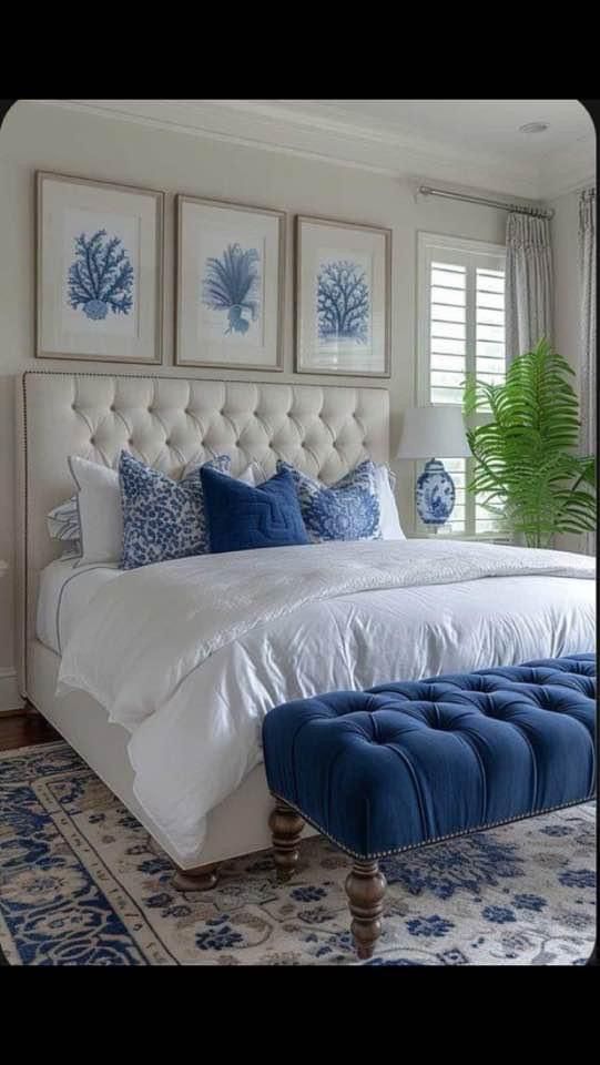 a bedroom with blue and white decor on the walls, an upholstered bed, and two framed pictures above it