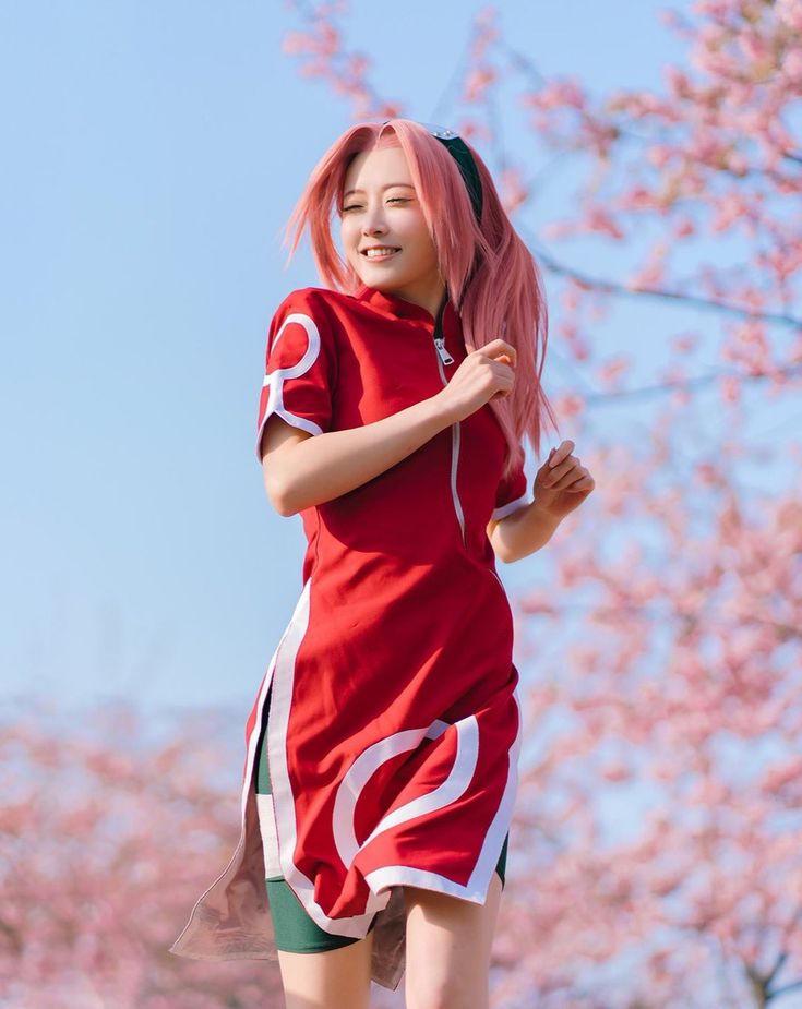 a woman with pink hair is running on the grass in front of cherry blossom trees