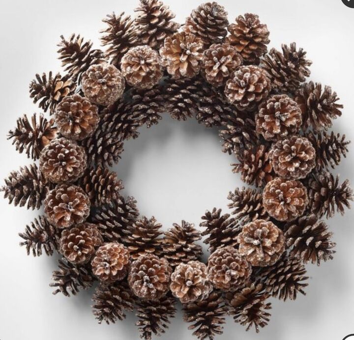 a wreath made out of pine cones on top of a white background with the words christmas written below it