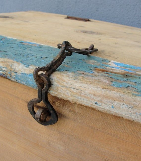 an old rusty chain is attached to the side of a piece of wood that has been painted blue