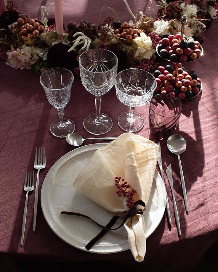 the table is set with wine glasses, silverware and napkins