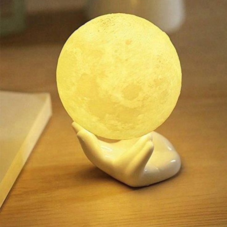 a yellow moon lamp sitting on top of a wooden table