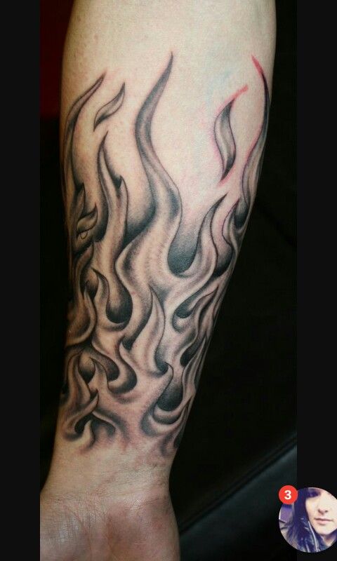 a person with a tattoo on their arm that has flames coming out of the top