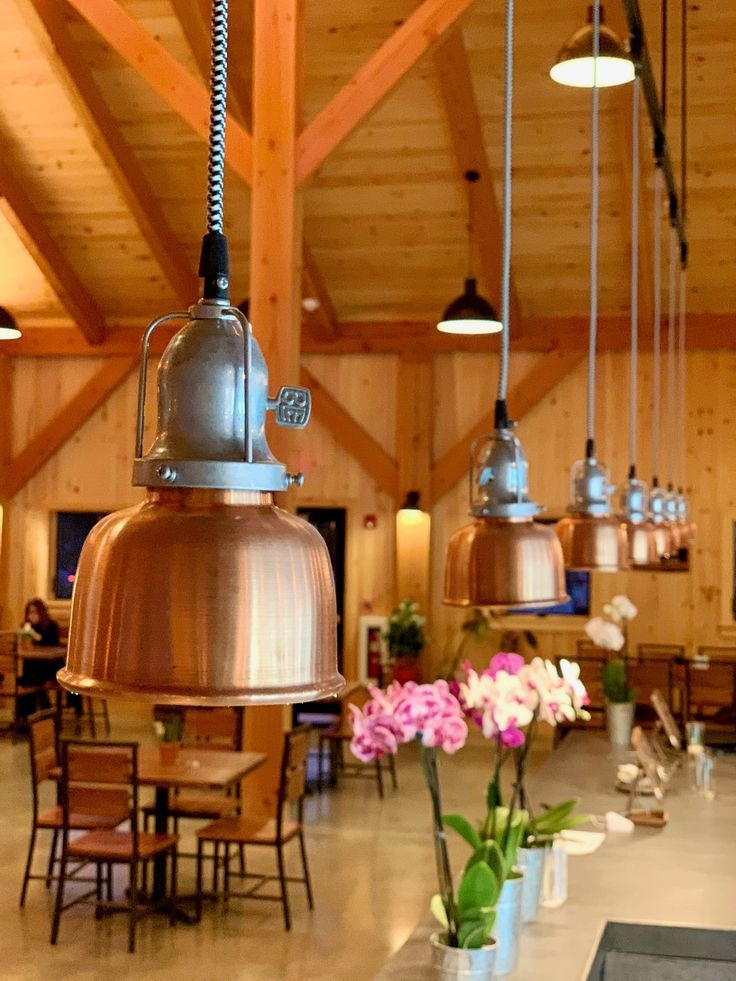 a restaurant with tables and hanging lights in the ceiling, flowers are on the table