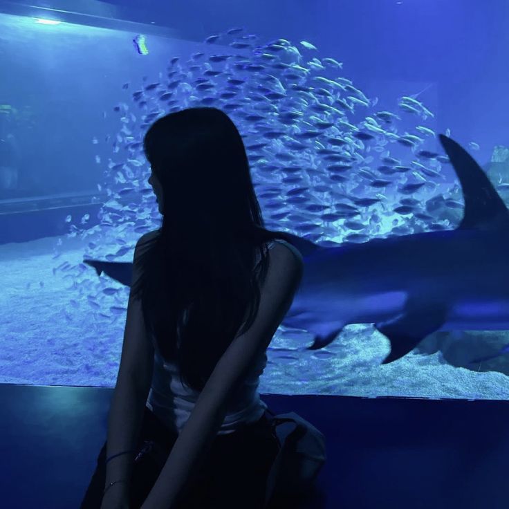 a woman sitting in front of a shark tank