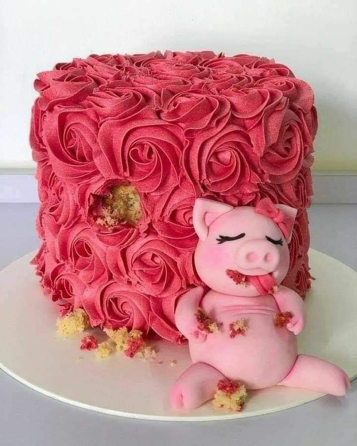 a pink cake decorated with roses and a pig laying on it's side in front of a white plate