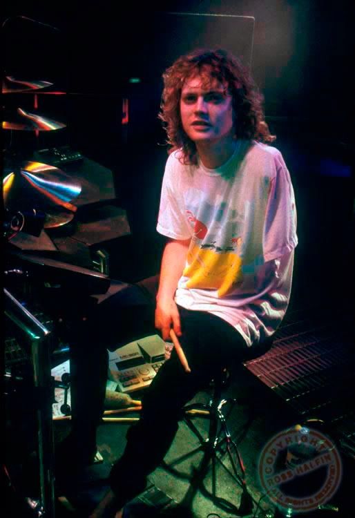 a young man sitting on top of a drum set in front of a microphone and drumstick