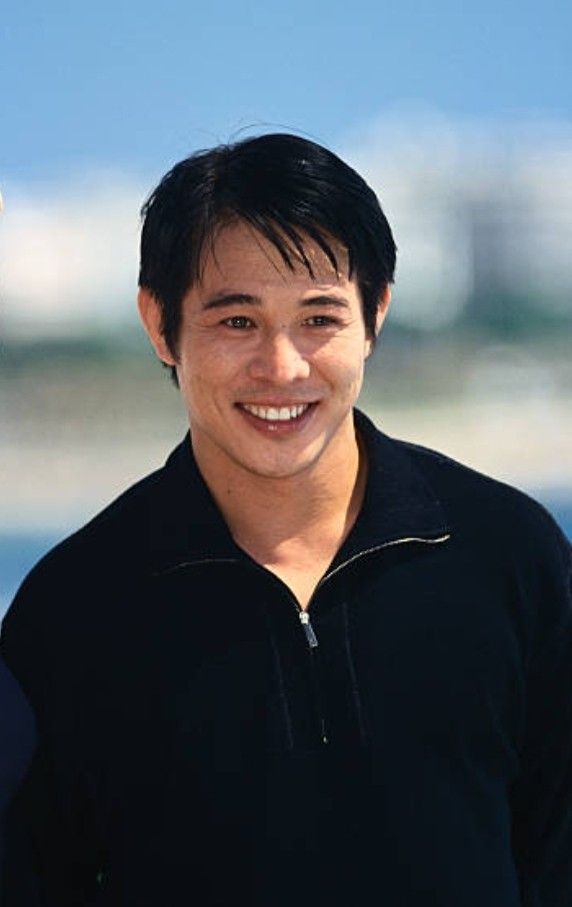 a man standing next to another man in front of the ocean smiling at the camera