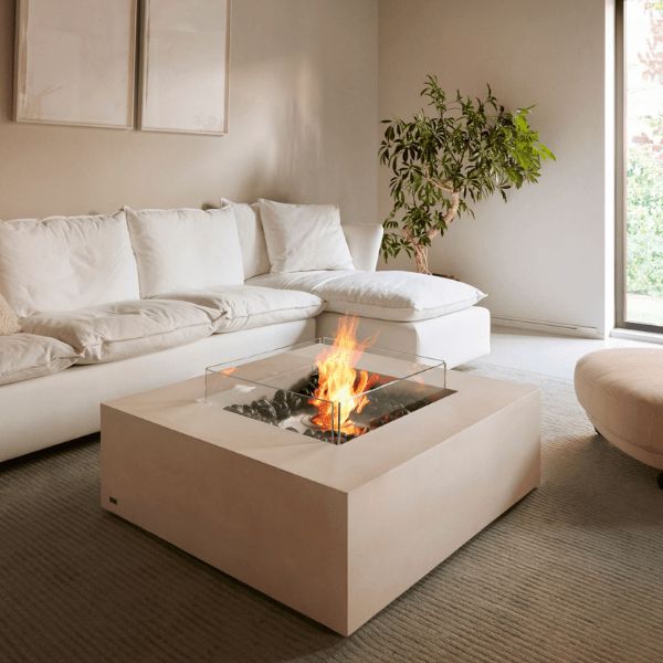 a living room with a white couch and fire pit in the middle of the floor