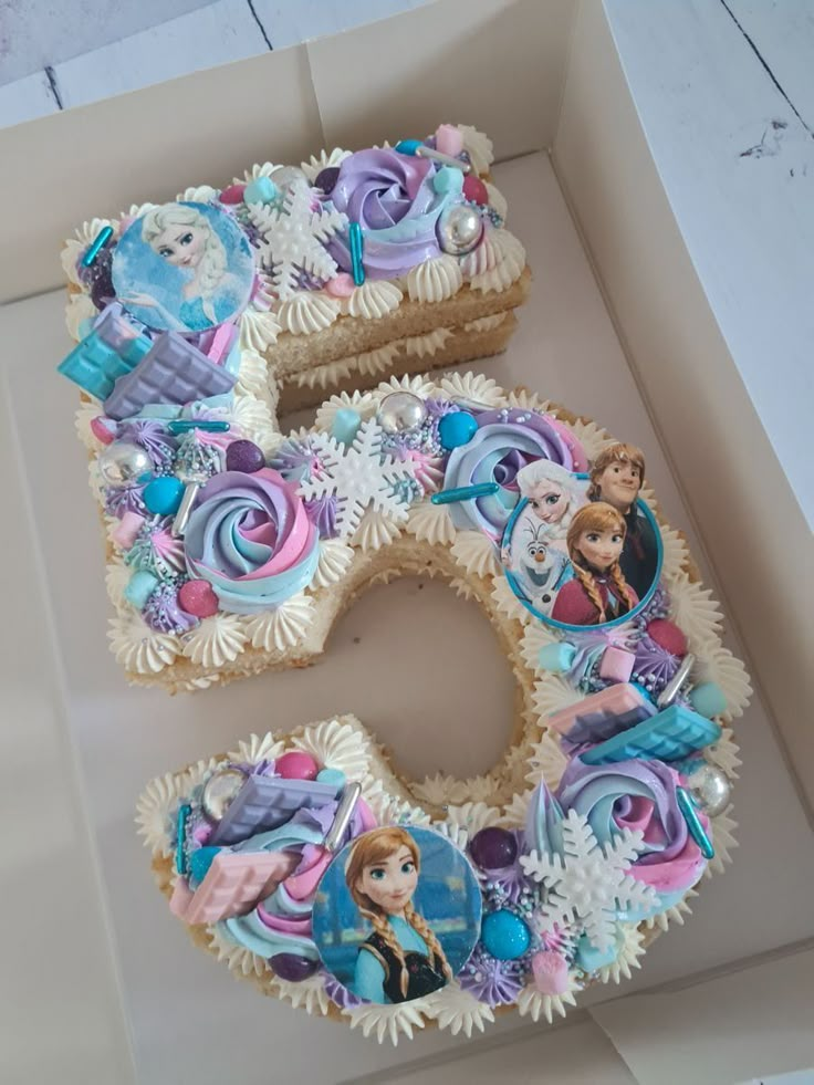 there is a birthday cake in the shape of the number five with princesses on it