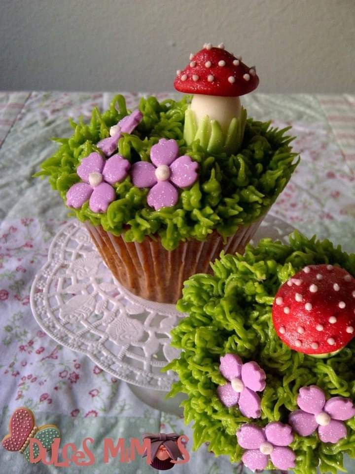 two cupcakes are decorated with flowers and mushrooms