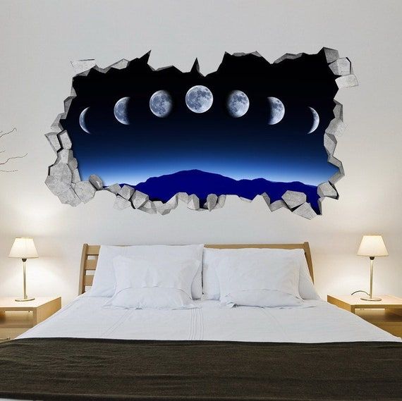 a bed with white sheets and pillows in front of a wall that has the moon on it