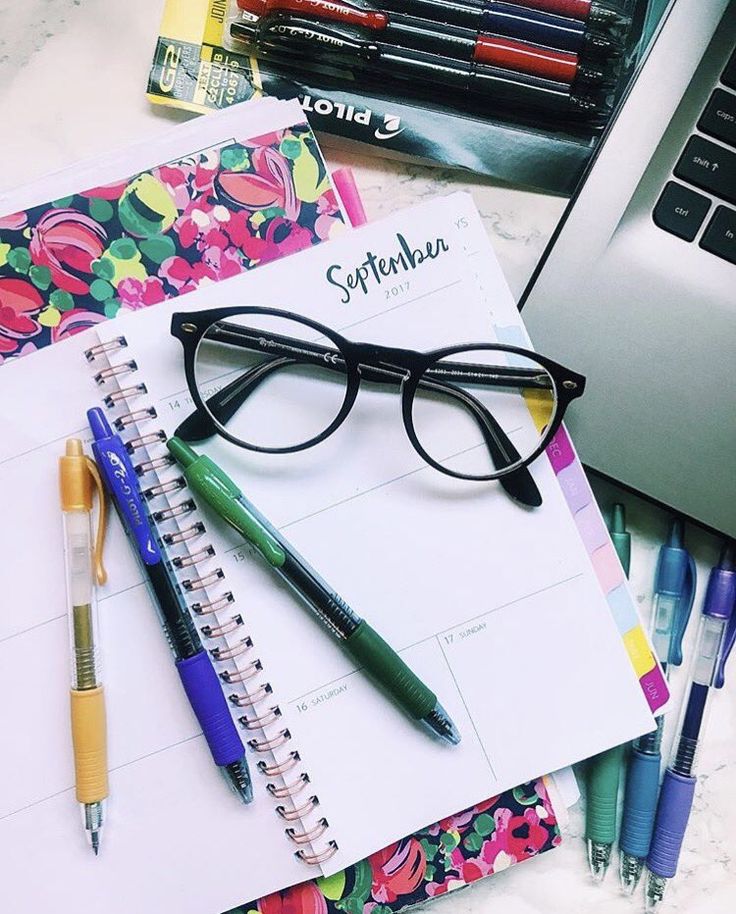 a notebook, pen and glasses on top of a desk