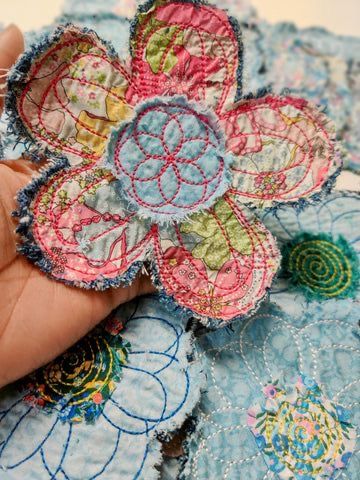 someone is stitching an applique flower onto fabric