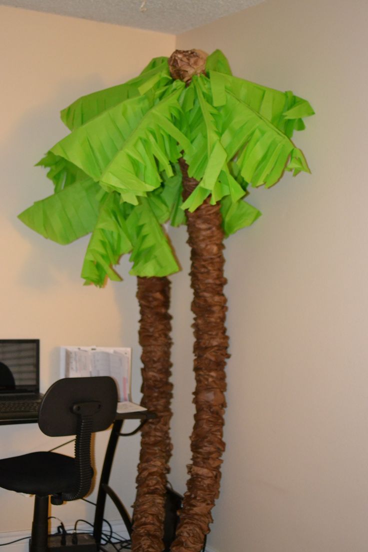 a palm tree sitting in the corner of a room next to a computer desk and chair