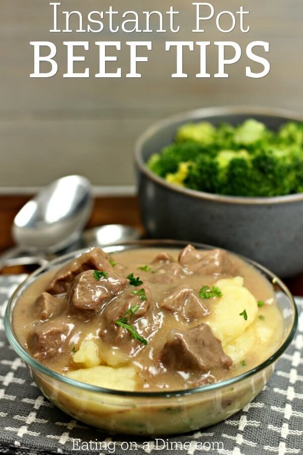 a glass bowl filled with beef and gravy on top of a checkered table cloth