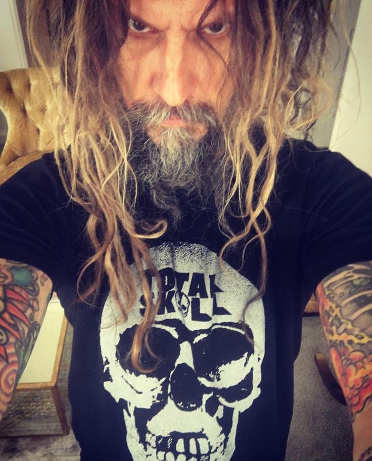 a man with long hair and beard wearing a black t - shirt that has a skull on it