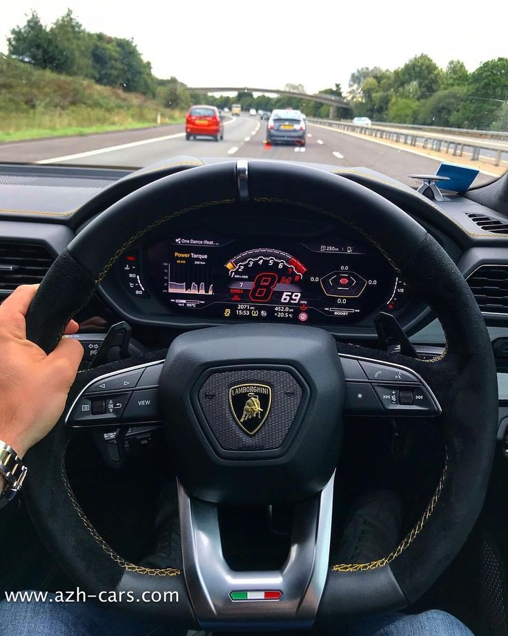 a person driving a car on the road with their hand on the steering wheel and other vehicles in the background