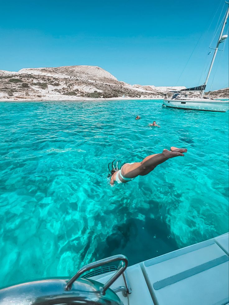 a man swimming in the ocean near boats