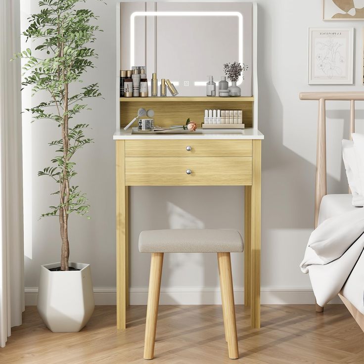 a bedroom with a vanity and stool next to a mirror on the wall, near a potted plant