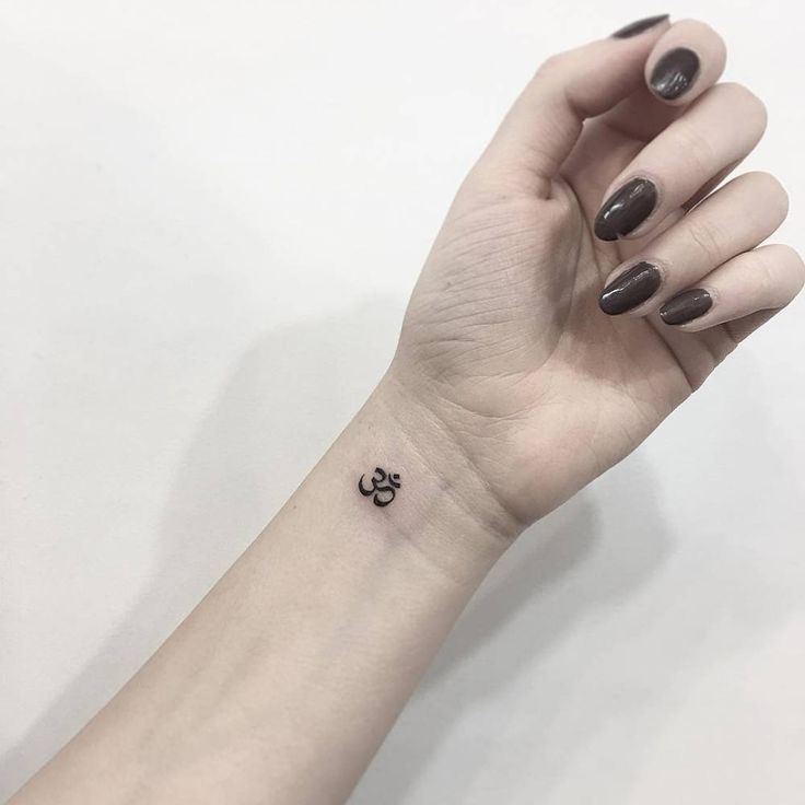 a woman's hand with a small tattoo on it, holding up her wrist