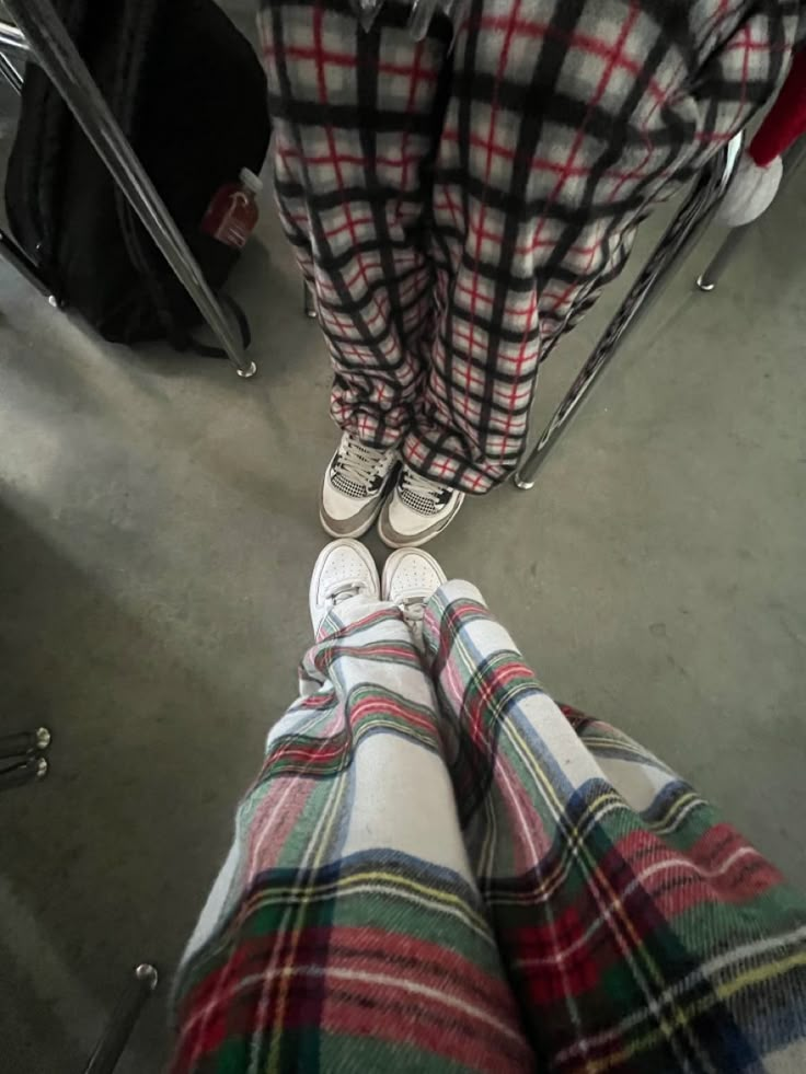 two people standing next to each other with plaid pants and sneakers on their feet in front of them