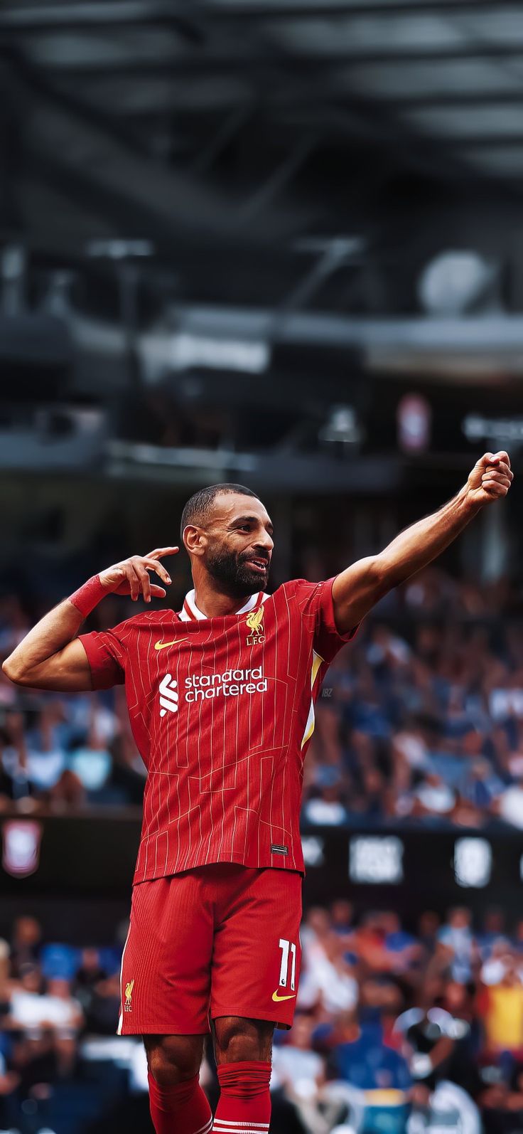 a man standing on top of a soccer field holding his arms out in the air