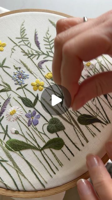 a person is stitching flowers on a white cloth with green and yellow trims