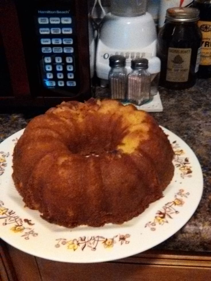 a bundt cake sitting on top of a white plate next to a coffee maker